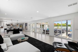 Ein modernes Wohnzimmer mit einer Couch, einem Couchtisch und Blick auf eine Terrasse mit Gartenmöbeln.