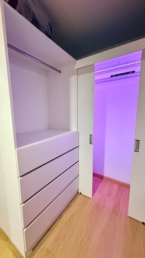 A room with a built-in wardrobe, a wooden floor, and a door leading to another room.
