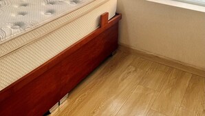 Een slaapkamer met een groot raam, een bed en uitzicht op een stadsbeeld.