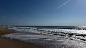 Una spiaggia con onde, un molo e cielo sereno.