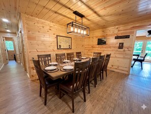 Ein Holzinterieur mit einem für sechs Personen gedeckten Esstisch, Holzwänden, einer Karte und einem Schild, das einen Wanderweg zeigt.