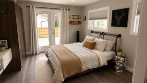 A bedroom with a bed, a bedside table, a window, and a door. - Epic home base under the chief with unbelievable back yard (Squamish)