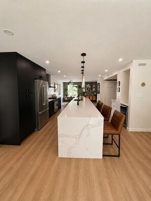 A modern kitchen with a marble island, black cabinets, stainless steel appliances, and a central pendant light. - Epic home base under the chief with unbelievable back yard (Squamish)