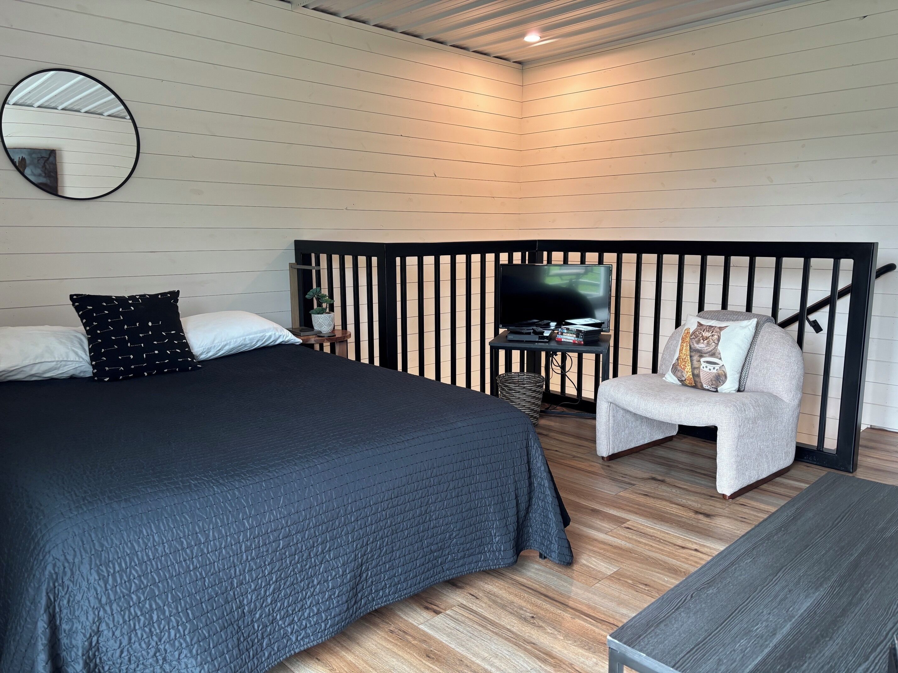 Une chambre à coucher avec un lit, une chaise, un téléviseur et une petite table.
