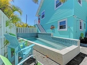 A turquoise house with a small pool, a white fence, and a staircase leading to the door. - Coco's Island Retreat: Near Gulf, Bay, Bridge St by Anna Maria Life Vacation Rentals (Bradenton Beach)