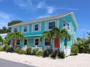 A two-story house with a red door, white trim, and a white picket fence. - Coco's Island Retreat: Near Gulf, Bay, Bridge St by Anna Maria Life Vacation Rentals (Bradenton Beach)