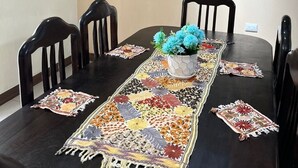 A dining table with a floral runner, a vase with blue flowers, and four chairs. - Modern and cozy apartment in Quetzaltenango (Quetzaltenango)