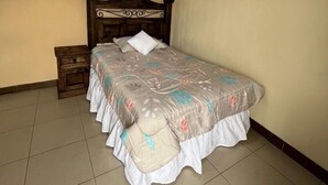 A bed with a floral bedspread, a wooden headboard, and a nightstand with a drawer. - Modern and cozy apartment in Quetzaltenango (Quetzaltenango)