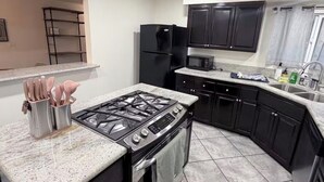 Uma cozinha com fogão a gás, forno, armários pretos, micro-ondas e uma pia de aço inoxidável.