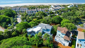 Un hotel frente al mar con varias construcciones, vistas a la playa y abundante vegetación.