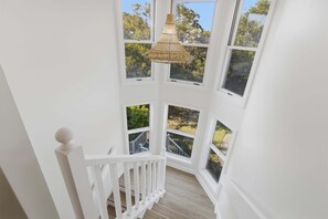 A white interior with multiple windows and a hanging light fixture. - 1 Pelican- Easy Walk to Beach & Community Pool, Lagoon View! (Isle Of Palms)