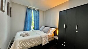 Un dormitorio con cama, armario y ventana con cortinas.