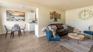A living room with a sofa, chairs, a coffee table, and a clock on the wall.