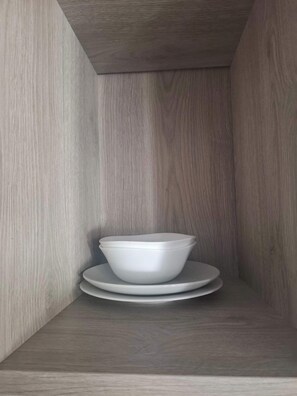 Ein Eckbereich eines Raumes mit einer Holzwand und einer weißen Schüssel auf einem Teller auf einem Regal.