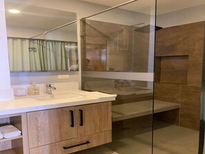 Ein modernes Badezimmer mit Duschkabine aus Glas, einem weißen Waschbecken und Holzschränken.