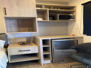 Eine kleine Küchenzeile mit Mikrowelle, Kaffeemaschine und Kühlschrank.
