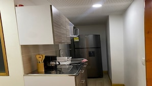 Una cocina compacta equipada con refrigerador, microondas y cafetera.