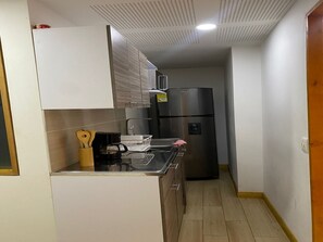 Eine kleine Küche mit Kühlschrank, Mikrowelle und Kaffeemaschine.