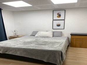 Ein Schlafzimmer mit Bett, Nachttisch, Schreibtisch und zwei gerahmten Kunstwerken an der Wand.