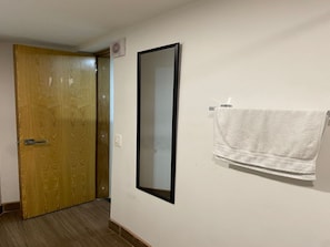 Ein Flur mit einer Holztür, einem an der Wand befestigten Spiegel und einem Handtuchhalter mit einem Handtuch.