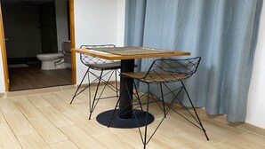 A dining area with a table and chairs, a visible toilet, and a blue curtain. - Global Executive Suites 203 (Medellín)