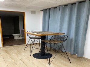 Ein Essbereich mit Tisch und Stühlen, einer sichtbaren Toilette und einem blauen Vorhang.