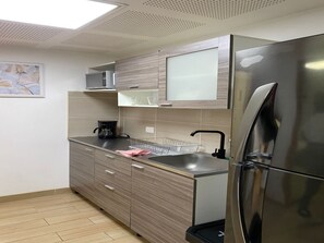 Eine moderne Küche mit einem Edelstahl-Kühlschrank, Holzschränken, einer Kaffeemaschine und einem Gläser-Ablagegestell.
