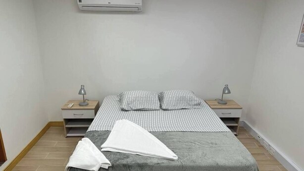 Un dormitorio con cama, dos mesitas de noche, aire acondicionado y una mesilla.