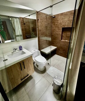 Ein modernes Badezimmer mit Duschkabine aus Glas, einem Waschbecken mit Seifenspender und einer Toilette.