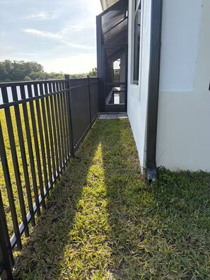A narrow pathway leading to a building entrance with a black metal fence on one side. - Naples Vacation Paradise -  Lake & Pool Views (Naples)
