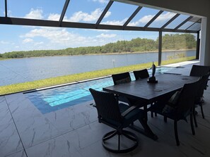 A covered outdoor dining area with a view of a lake and grassy area. - Naples Vacation Paradise -  Lake & Pool Views (Naples)