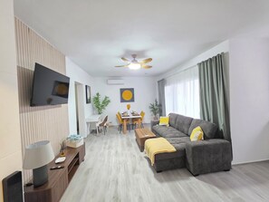 A modern living room with a sofa, dining table, and TV. - Laguna Beach 409 4 Min Walk to Playa Dominicus (Dominicus)