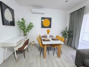 A dining area with a white table, yellow chairs, and a potted plant. - Laguna Beach 409 4 Min Walk to Playa Dominicus (Dominicus)