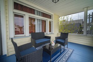 Eine überdachte Veranda mit Korbmöbeln und einem Glastisch.