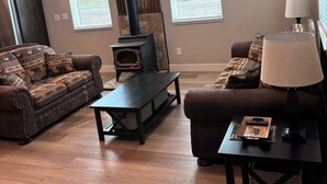 A living room with a fireplace, two sofas, a coffee table, a lamp, and a clock on the wall. - Beautiful 2-bedroom house in Smoot perfect for a relaxing getaway. (Smoot)