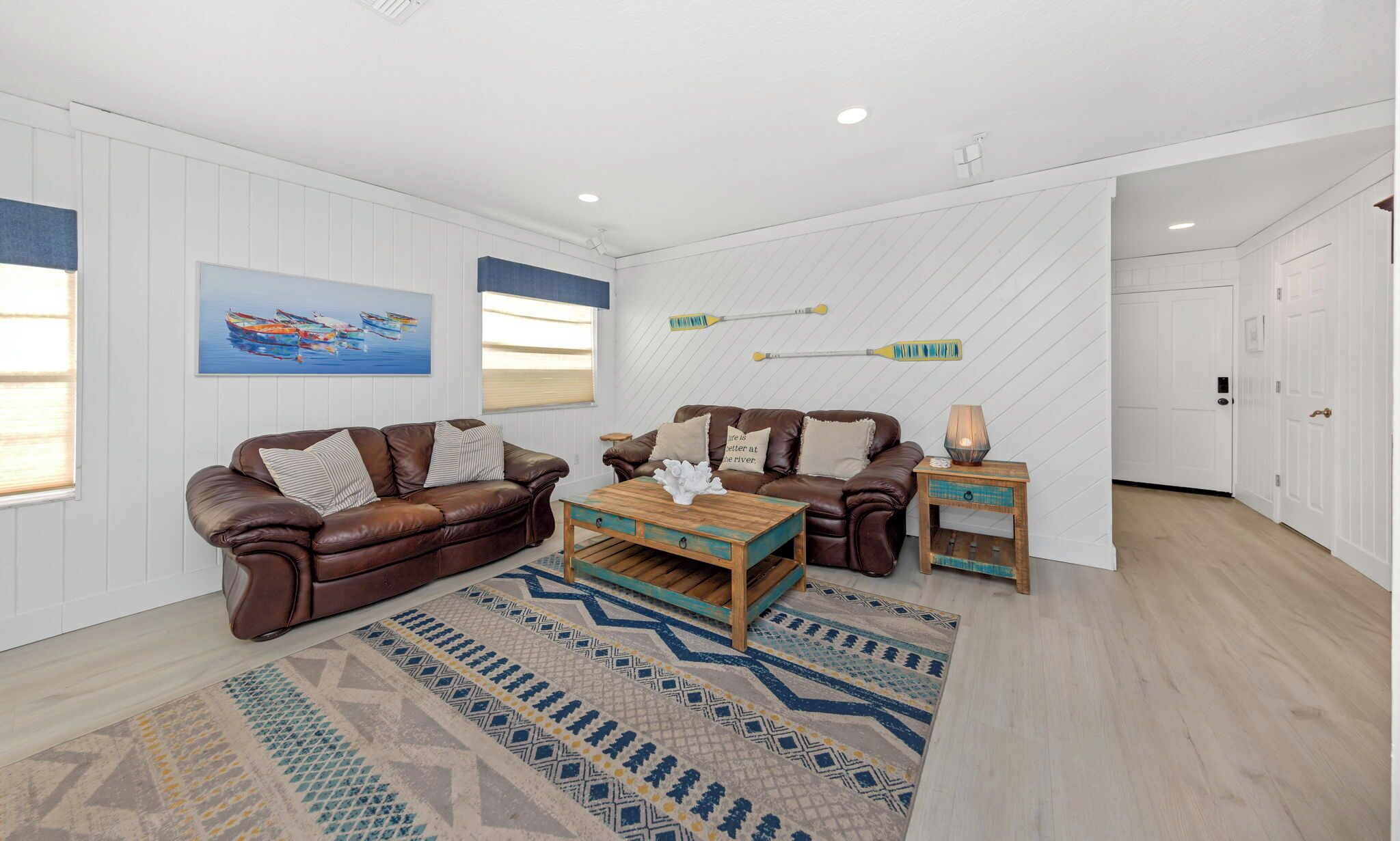 A living room with two brown leather sofas, a wooden coffee table, and a patterned rug.