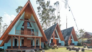 Un edificio moderno de techo triangular con balcón, una fogata y una mesa de picnic en el patio.