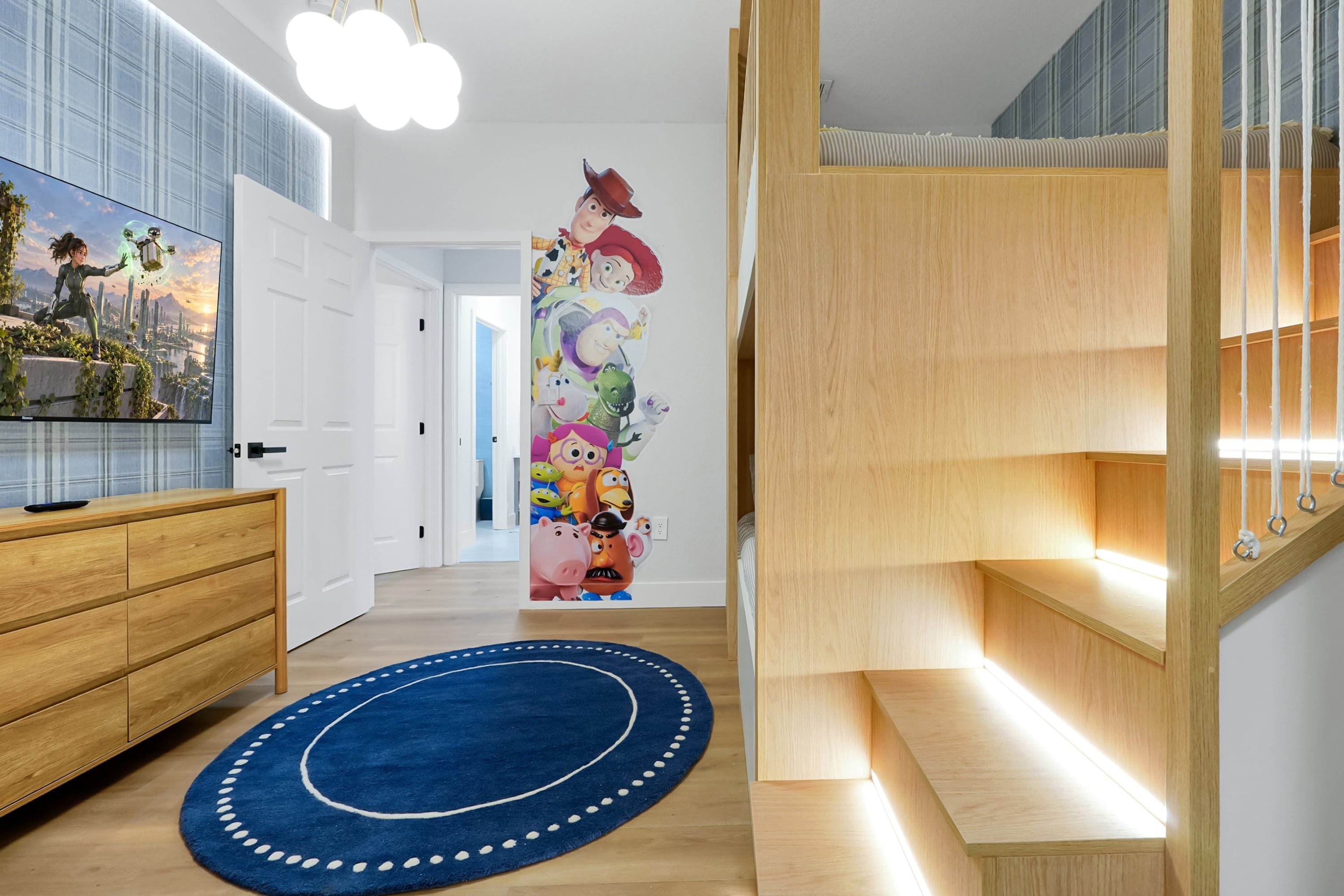 Un intérieur moderne avec un escalier en bois, un tapis bleu et un mur décoré de personnages animés.