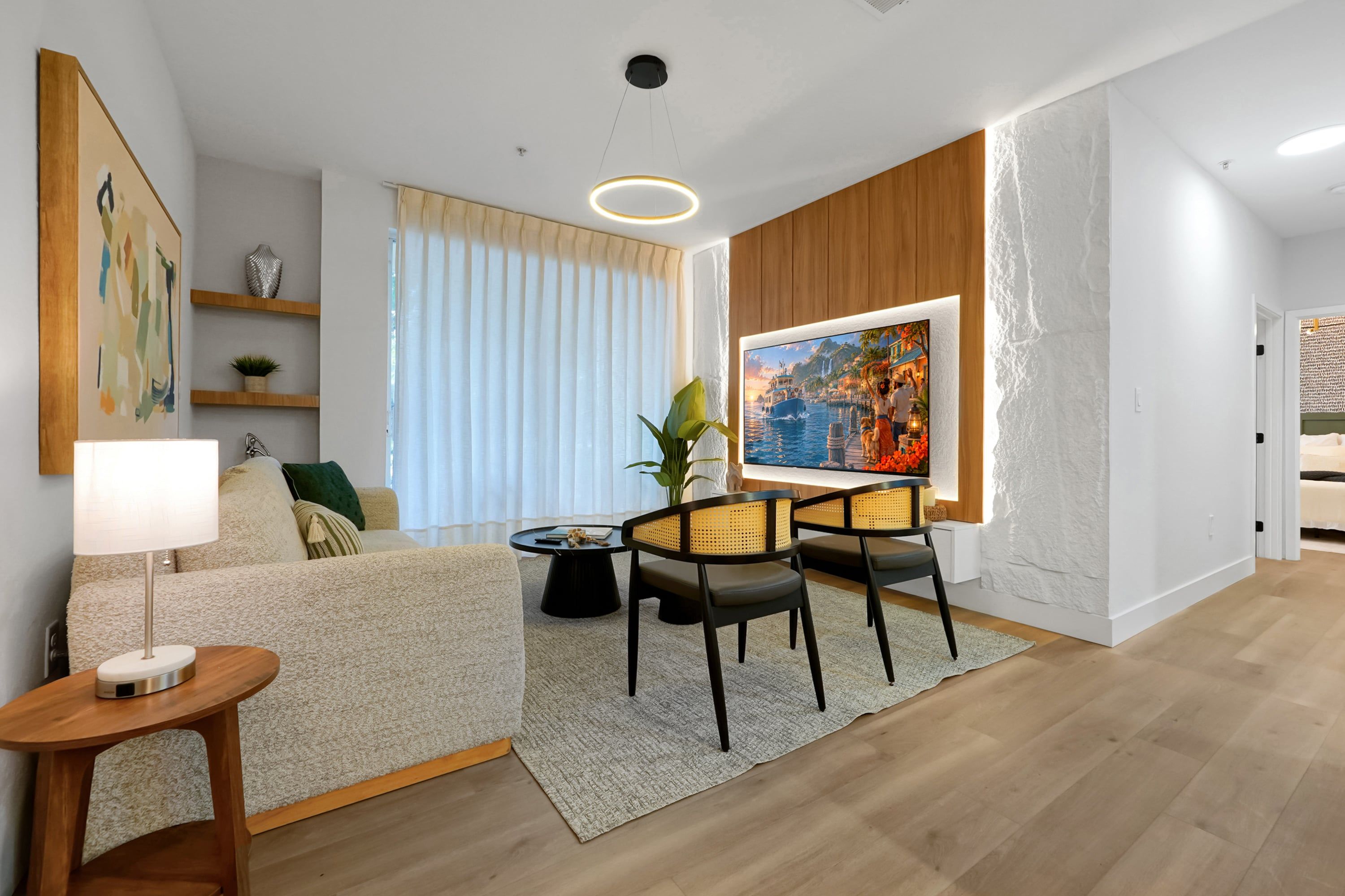 Uma sala de estar moderna com sofá, mesa de centro e área de jantar com cadeiras. Há um quadro na parede e uma janela com cortinas.