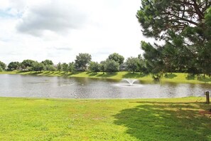 A serene park with a pond, trees, and a fountain. - Legacy Dunes Retreat Near Disney (Kissimmee)