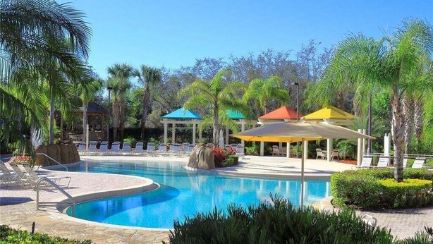 A swimming pool with lounge chairs, palm trees, and covered areas. - Legacy Dunes Retreat Near Disney (Kissimmee)