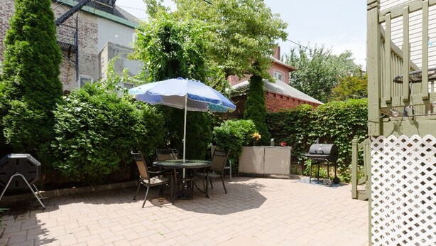Un patio con una mesa y sillas, una parrilla y una valla de celosía blanca.