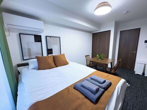 Ein Hotelzimmer mit Bett, Schreibtisch, Stuhl, Pflanze und Tür.