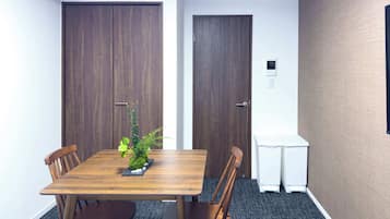 Ein Konferenzraum mit einem Holztisch, vier Stühlen, einer kleinen Pflanze und zwei Türen.