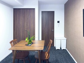 Une salle de conférence avec une table en bois, quatre chaises, une petite plante et deux portes.