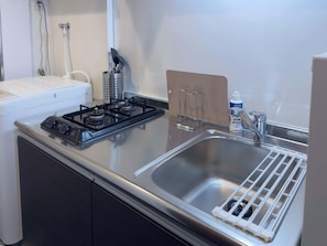 Une cuisine équipée d’une cuisinière, d’un évier et d’un porte-ustensiles.