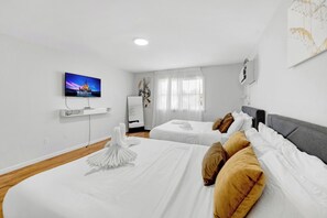 Habitación de hotel con dos camas, un televisor de pantalla plana, un espejo y un cuadro en la pared.