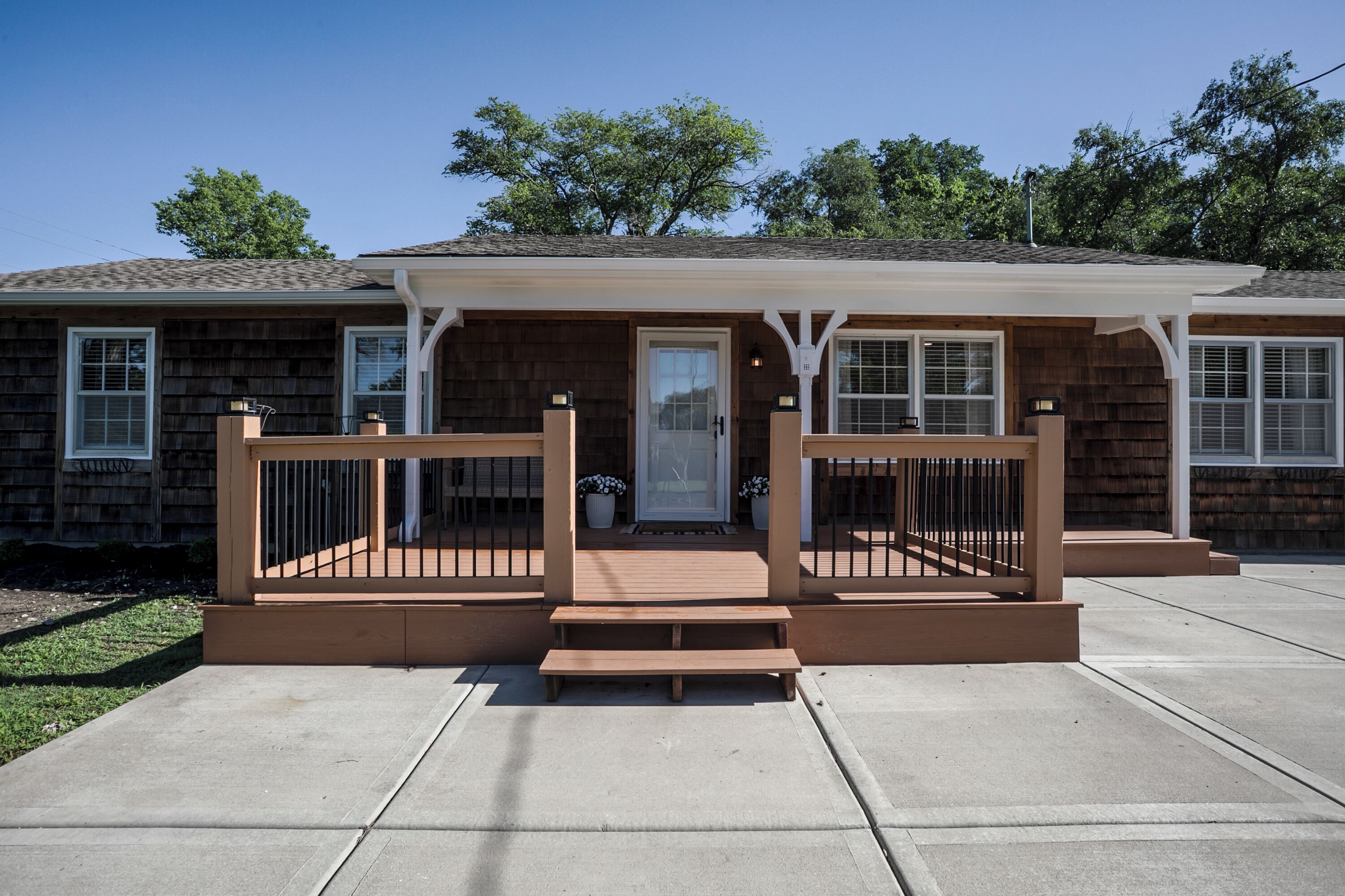Une maison à deux étages avec un porche à l’avant, une terrasse en bois et une porte d’entrée.