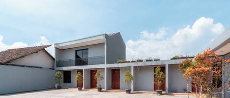 A courtyard with a modern building, potted plants, and a clear sky.