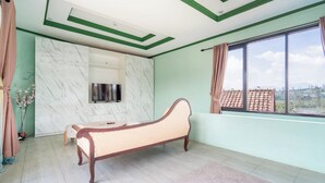 Ein Schlafzimmer mit einem Bett, einem Fernseher, einer Marmorwand und einem Fenster mit Blick.